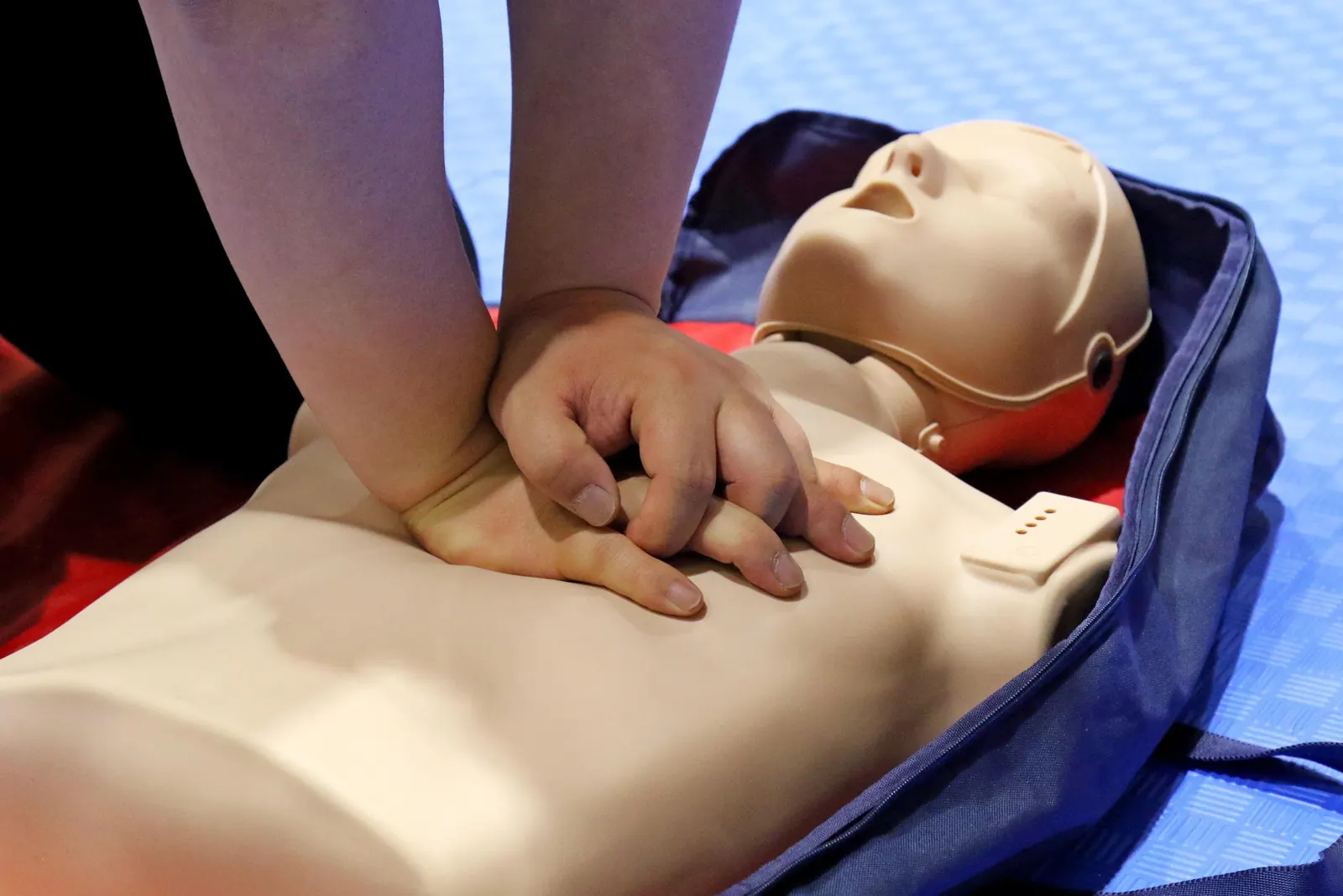 Hands practicing chest compressions on a CPR manikin